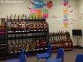 two shelves holding many guitars in a classroom setting