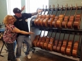 A man and woman embracing and smiling while pointing towards a two-tiered guitar shelf