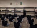 rows of empty blue chairs facing a wall lined with an empty shelving system