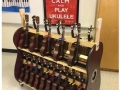 a two tiered ukulele rack placed in front a red poster