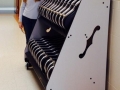 A woman, in a school hallway, standing and smiling next to a cart filled with black violin cases